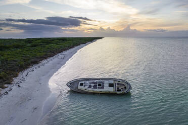 Aerial view of a shipwreck along the coast at sunset in Punta Escolleras, Rio Lagartos natural park, Yucatan, Mexico. - AAEF18251