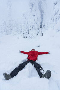 Cheerful woman smiling lying down in the snow, Lapland, Finland, Europe - RHPLF24184