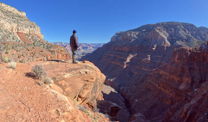A hiker looking out from a cliff in Hermit Canyon at Grand Canyon, Grand Canyon National Park, UNESCO World Heritage Site, Arizona, United States of America, North America - RHPLF24346