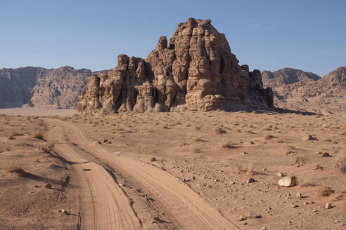 Off-road vehicle tracks in the sand of Wadi Rum leading to a rocky mountain, Wadi Rum, Jordan, Middle East - RHPLF24372