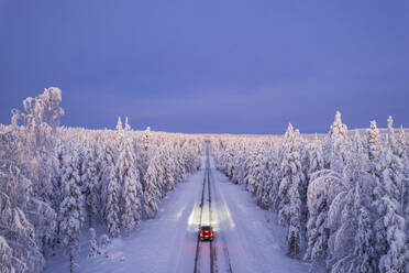 Overhead view of a car driving on empty, icy and slippery road with illuminated headlamps, Akaslompolo, Kolari, Pallas-Yllastunturi National Park, Lapland region, Finland, Europe - RHPLF24496