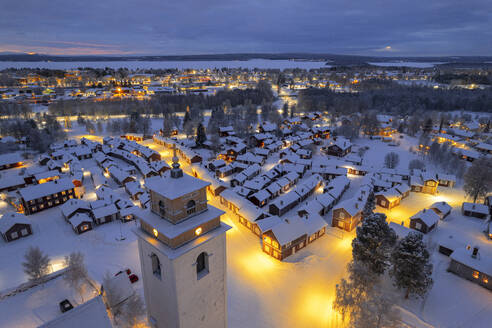 Aerial view of illuminated cottages and bell tower covered with snow in the old village of Gammelstad Church Town at dusk, UNESCO World Heritage Site, Lulea, Norrbotten, Norrland, Sweden, Scandinavia, Europe - RHPLF24501