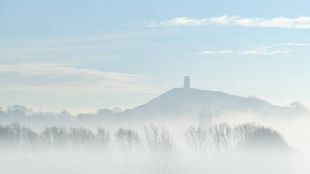 St. Michael's Tower on Glastonbury Tor above the tower of St. John the Baptist's Church on a misty morning in winter, Glastonbury, Somerset, England, United Kingdom, Europe - RHPLF24617
