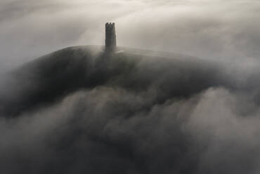 Aerial view of St. Michael's Tower on Glastonbury Tor surrounded by a sea of mist in winter, Glastonbury, Somerset, England, United Kingdom, Europe - RHPLF24662