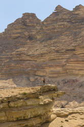 Man standing on cliff against mountains, Wadi Sinaq, Dhofar Governorate, Oman, Middle East - RHPLF24962