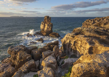 Waves crashing against rock stack at Cabo Carvoeiro in evening sunlight with Ilha da Berlenga in the distance, Peniche, Centro Region, Estremadura, Portugal, Europe - RHPLF25081