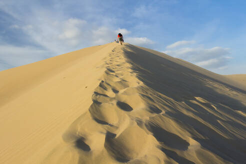 People walking up sand dune, Huacachina, Peru, South America - RHPLF25301