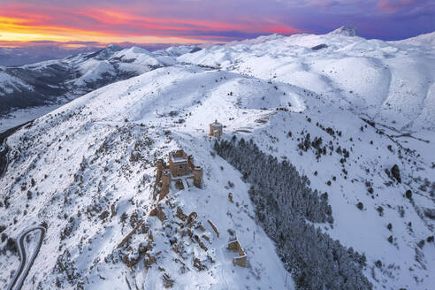 Aerial winter view of the snow covered Rocca Calascio castle and church of Santa Maria della Pieta,�with pink clouds at sunset, Rocca Calascio, Gran Sasso e Monti della Laga National Park, Campo Imperatore, L'Aquila province, Abruzzo, Italy, Europe - RHPLF25318