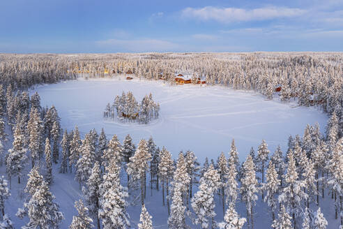 Aerial view of a tourist winter resort in the snow covered forest and the frozen lake in Kangos, Pajala, Norrbotten, Norrland, Lapland, Sweden, Scandinavia, Europe - RHPLF25320