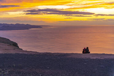 View of couple overlooking volcanic coastline from Mirador del Rio at sunset, Lanzarote, Las Palmas, Canary Islands, Spain, Atlantic, Europe - RHPLF25507