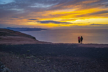 View of couple overlooking volcanic coastline from Mirador del Rio at sunset, Lanzarote, Las Palmas, Canary Islands, Spain, Atlantic, Europe - RHPLF25508