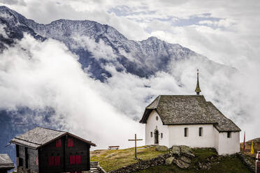Foggy sky over the small church in the alpine village of Bettmeralp, canton of Valais, Switzerland, Europe - RHPLF25626