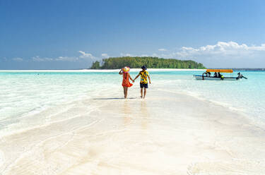 Man and woman in love holding hands walking on empty sandy shore surrounded by the Indian Ocean, Zanzibar, Tanzania, East Africa, Africa - RHPLF25628