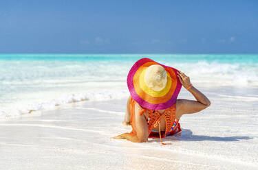 Woman with hat relaxing on idyllic empty beach, Zanzibar, Tanzania, East Africa, Africa - RHPLF25638