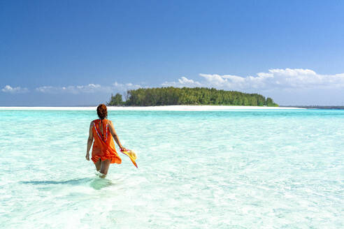 Woman admiring an exotic island standing in the crystal blue sea, Zanzibar, Tanzania, East Africa, Africa - RHPLF25639