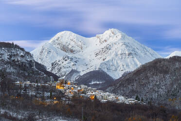 The small illuminated village of Pietracamela covered with snow and surrounded by Intermesoli snowy peak at dusk, Gran Sasso and Monti della Laga National Park, Apennines, Teramo district, Abruzzo region, Italy, Europe - RHPLF25885