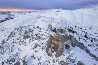 Aerial winter view of Rocca Calascio castle and the Santa Maria della Pietà church in the snowy landscape at dusk, Campo Imperatore, L'Aquila province, Abruzzo region, Italy, Europe - RHPLF26010