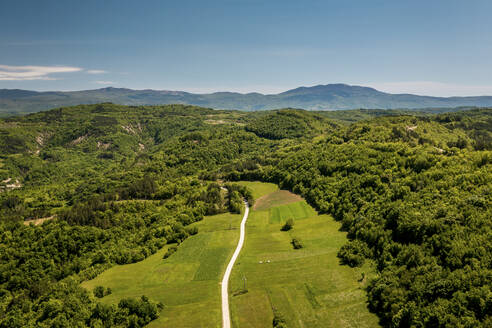 Aerial view of a road leading to Ucka mountain in the background, Central Istria in Croatia. - AAEF18362