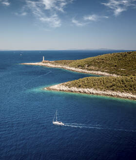 Aerial view of Stoncica lighthouse and a sailing boat on the island of Vis during summer, Dalmatia, Croatia. - AAEF18397