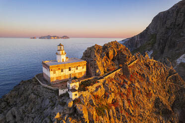 Aerial view of Punta della Guardia lighthouse on top of a cliff on the island of Ponza, lit from sunrise, Ponza island, Pontine islands, Mediterranean Sea, Latium, Lazio, Italy, Europe - RHPLF26050