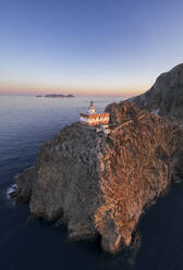 Panoramic aerial view of Ponza island lighthouse, Punta della Guardia, standing on top of a cliff facing the sea at dusk, Ponza island, Pontine islands, Mediterranean Sea, Latium, Lazio, Italy, Europe - RHPLF26055