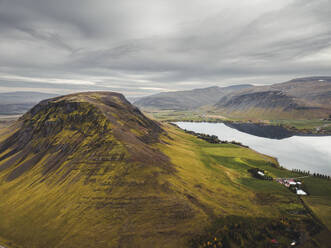 Aerial view of mountain landscape at sunset with a small lake and overcasted sky in Iceland. - AAEF18572