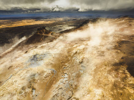 Aerial view of a volcanic hot spring with sulphuric smoke and a lake in background, Namafjall Hverir viewpoint, Northeastern Region, Iceland. - AAEF18612