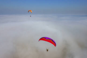 Aerial view of two paramotors flying above fog and clouds on the Black Sea coast of Istanbul, Turkey. - AAEF18788