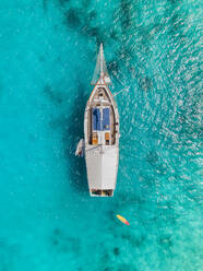 Aerial view of a sailing boat navigating the Caribbean Sea along the coastline in Aruba island. - AAEF18919