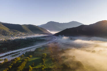 Aerial view of vehicles on the highway road at sunrise with low clouds and fog among the mountains in Psaka, Epirus, Greece. - AAEF19035