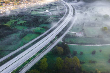 Aerial view of vehicles on the highway road at sunrise with low clouds and fog among the mountains in Psaka, Epirus, Greece. - AAEF19036