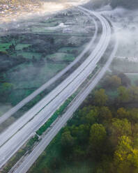 Aerial view of vehicles on the highway road at sunrise with low clouds and fog among the mountains in Psaka, Epirus, Greece. - AAEF19037