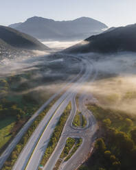 Aerial view of vehicles on the highway road at sunrise with low clouds and fog among the mountains in Psaka, Epirus, Greece. - AAEF19038
