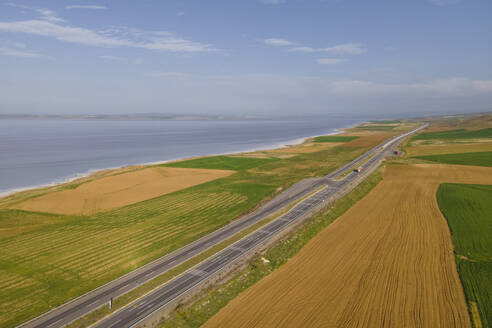 Aerial view of a road driving along the Tuz Golu (Lake Tuz), one of the largest hyper saline lake in the world, Central Anatolia Region, Turkey. - AAEF19067