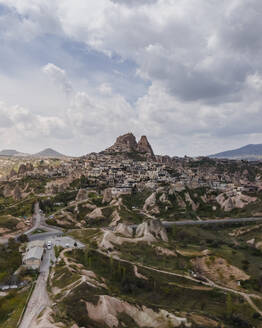 Aerial view of Uchisar, an old village huddled around the base of a huge rock cone with castle on top, Nevsehir, Cappadocia region, Turkey. - AAEF19073