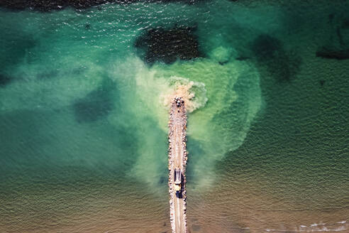 Aerial view of a heavy duty truck unloading stones into the Mediterranean Sea along the beach coastline in Follonica, Grosseto, Tuscany, Italy. - AAEF19192