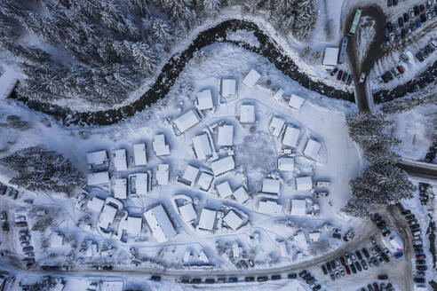 Aerial view of houses along the frozen Vieze river with snow in wintertime, Champery, Valais, Switzerland. - AAEF19201