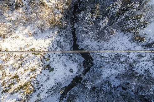 Aerial view of a footbridge crossing a small stream with snow in wintertime, Troistorrents, Valais, Switzerland. - AAEF19205