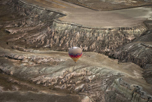 Aerial view of hot air balloon at sunrise flying over Goreme valley and national park, Nevsehir, Cappadocia, Turkey. - AAEF19210