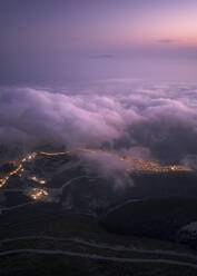 Aerial view of a road across the mountains at sunset with low clouds, Himare, Vlore, Albania. - AAEF19215