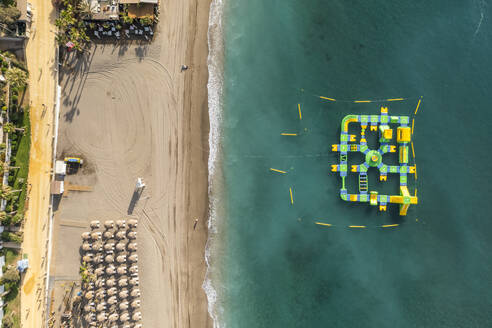 Aerial view of an inflatable beach game along Playa Casablanca beach in Marbella, Andalusia, Spain. - AAEF19244