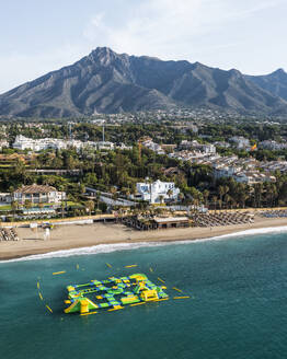 Aerial view of an inflatable beach game along Playa Casablanca beach in Marbella, Andalusia, Spain. - AAEF19247