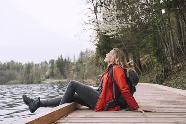 Hiker resting by lake sitting on boardwalk - NDEF00701