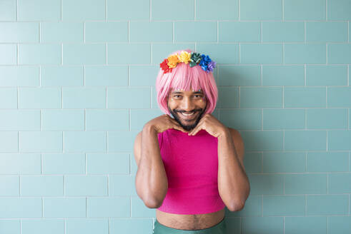 Smiling man wearing pink wig standing in front of wall - VRAF00125