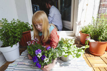 Blondes Mädchen hält Pflanze auf dem Balkon - IHF01383