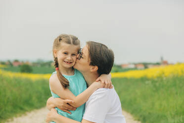 Mother kissing daughter at field - VSNF00948