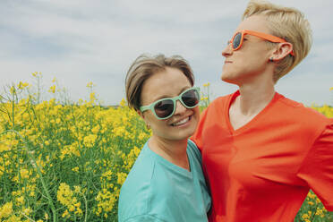 Happy lesbian couple wearing sunglasses at field - VSNF00954