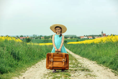 Glückliches Mädchen stehend mit Vintage-Koffer - VSNF00959