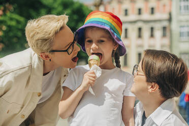Lesbian couple enjoying with daughter eating ice cream - VSNF00995