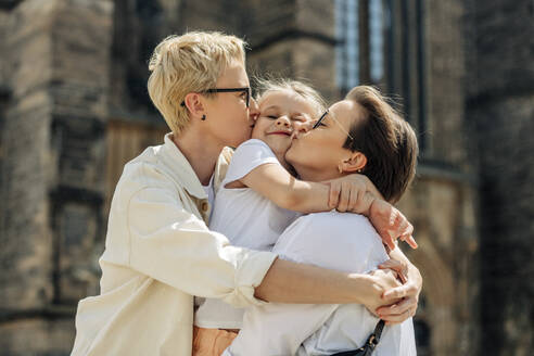 Lesbian couple kissing daughter at sunny day - VSNF01001